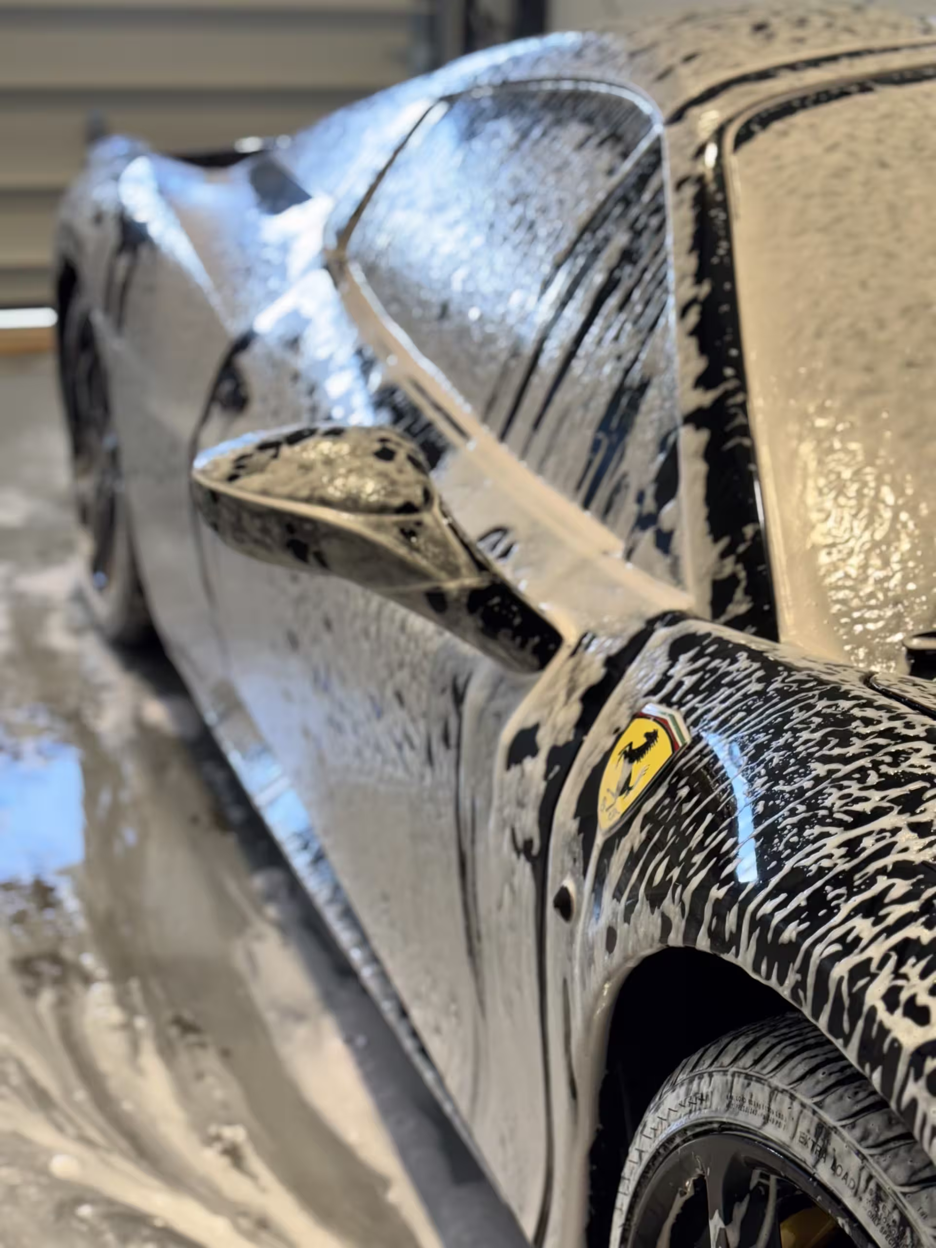 Close-up of a Ferrari covered in hand-wash foam